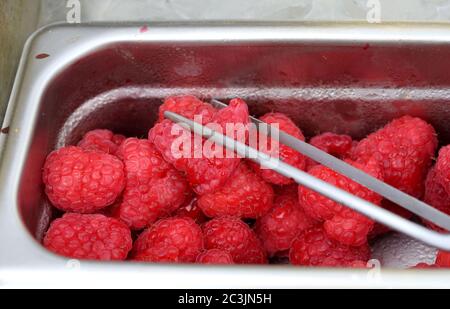 Rohe Himbeeren in einem Behälter mit Zange Stockfoto