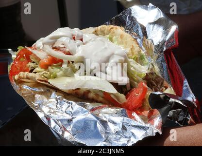 Ein Gyro-Sandwich gefüllt mit Lamm, Tomaten, weißen Zwiebeln, Salat und Zatziki-Sauce auf Pita-Brot Stockfoto