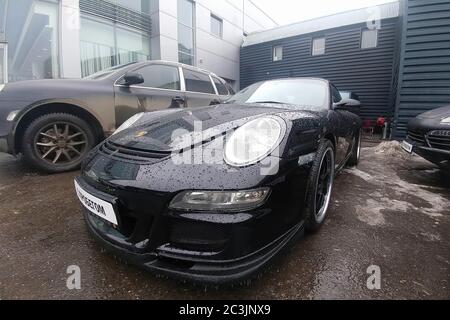 Moskau, Russland - 22. April 2019: Ein schwarzer Porsche 911 mit Aerodynamik-Kit steht auf dem Parkplatz im Service-Center. Regen fällt auf das Auto. Vorderansicht Stockfoto