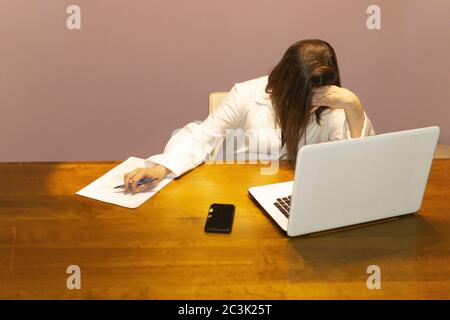 Nahaufnahme einer Ärztin an ihrem Schreibtisch in Vorderseite des Laptops mit müdem Ausdruck Stockfoto