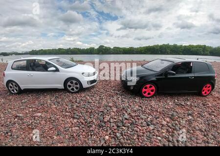 Moskau, Russland - 03. Mai 2019: Zwei Spielzeugautos Volkswagen Golf mk6 stehen auf einem Kiesstrand. Weiße und schwarze GTI stehen einander gegenüber Stockfoto