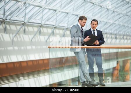 Zwei Geschäftsleute, die sich in einem modernen Büro informell treffen und Dokumente diskutieren Stockfoto