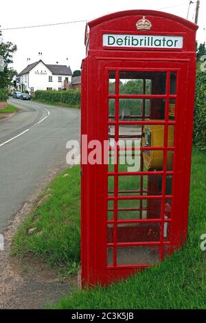 Defibrillator in roter britischer Telefonbox, Marbury Village, Cheshire, England, Großbritannien, AED, erste Hilfe für Herz - lebensrettend Stockfoto