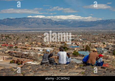 Familien auf einem Wanderweg im Petroglyph National Monument mit Blick auf die Stadt Albuquerque und die Sandia Mountains Stockfoto