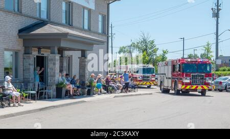 Die Fahrzeuge der örtlichen Feuerwehr ziehen an Bewohnern einer Altersresidenz vorbei, um während der Pandemie covid-19 ihre Stimmung zu erhöhen. Stockfoto