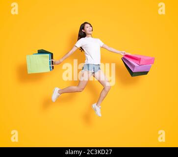 Glückliche junge Frau mit Einkaufstaschen und Springen Stockfoto