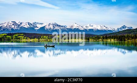 Angelboot auf Pyramid Lake im Jasper National Park, Alberta, Kanada mit den schneebedeckten Gipfeln der Rocky Mountains im Hintergrund Stockfoto