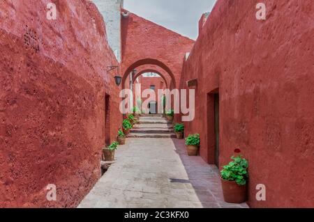 AREQUIPA, PERU - 17. JANUAR 2018: Schöne schmale Straße Sevilla mit Blumentöpfen und roten Kolonialbauten im Kloster Santa Catalina, Arequipa Stockfoto