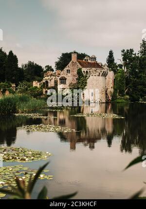 Vertikale Aufnahme der Spiegelung einer alten Burg auf Ein schöner Teich, umgeben von Bäumen Stockfoto