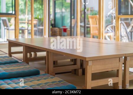 Kleine Holztische sind für lange Tisch japanischen Raum Stil auf der Matte in Glasraum, die für die Mittagszeit vorzubereiten angeordnet. Stockfoto