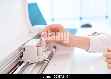Junge Frau in Druckerei Papier einlegen und Farbstifte auf Plotter Stockfoto