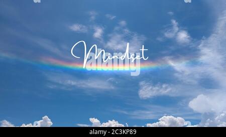 Inspirierendes Zitat geschrieben auf einem bewölkten Himmel mit einem Regenbogen. Botschaft mit dem Ausdruck Mindset. Nachricht oder Karte. Konzept der Inspiration, Achtsamkeit. Pos. Stockfoto