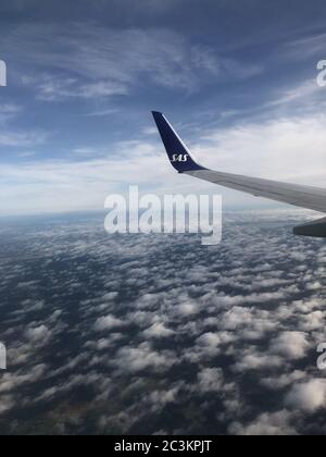 Vertikale Aufnahme der Wolken unter dem Flugzeugflügel Stockfoto