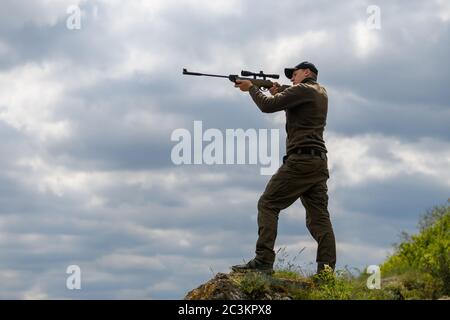 Schließen Sie Männchen mit einem Gewehr in der Jagdzeit. Jäger in Camouflage Kleidung Natur Hintergrund Stockfoto