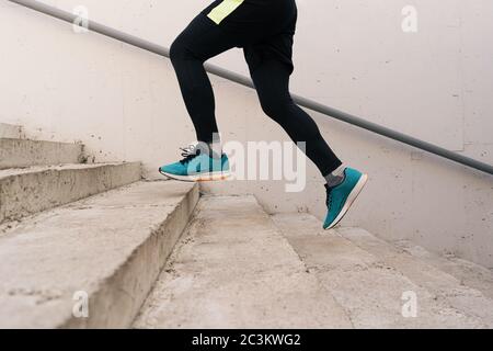 Junge Männer Beine laufen oben auf der Stadttreppe. Fitness, Sport, Menschen, Bewegung und Lifestyle-Konzept Stockfoto