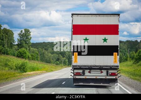 Ein LKW mit der Nationalflagge Syriens auf der Hintertür transportiert Güter in ein anderes Land entlang der Autobahn. Konzept Export-Import,transp Stockfoto