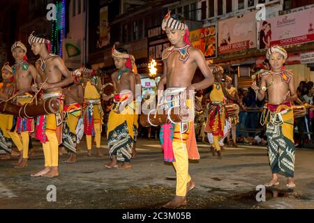 Junge Musiker, darunter Trommler und Tamburin-Spieler, treten während der Esala Perahera auf einer Straße in Kandy in Sri Lanka auf. Stockfoto