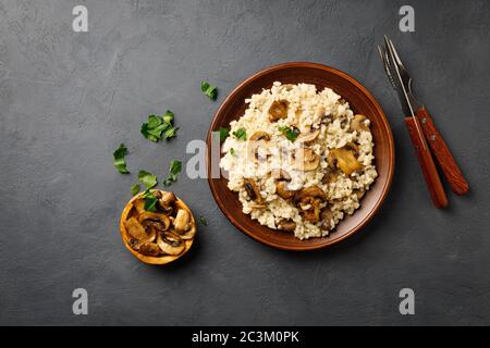 Traditionelle italienische Küche - vegetarisches Risotto mit Pilzen. Schwarzer Stein im Hintergrund. Stockfoto