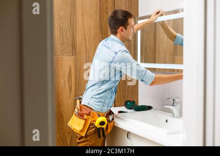 Klempner installiert Handtuchwärmer an der Wand im Bad. Stockfoto