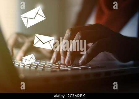 Muslimische Frau, die im Büro auf dem Laptop tippt, mit E-Mail-Symbolen, die verschickt werden. Kommunikationstechnologie. Nahaufnahme des Bildes mit selektivem Fokus Stockfoto