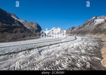 Atemberaubende Aussicht auf den Großen Aletschgletscher vom Wanderweg oben an einem sonnigen Sommertag mit blauem Himmel und schneebedeckten Schweizer Alpen im Hintergrund, o Stockfoto