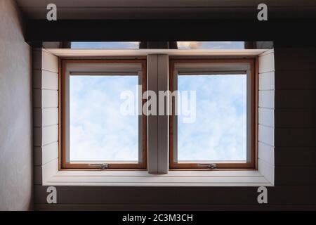 Zwei leere Fenster in Holzdecke mit blauem Himmel dahinter Stockfoto