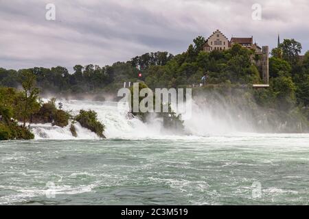 Atemberaubender Panoramablick auf den Rheinfall, den mächtigsten Wasserfall Europas am Hochrhein, an einem bewölkten Sommertag mit Schloss Laufen in Stockfoto