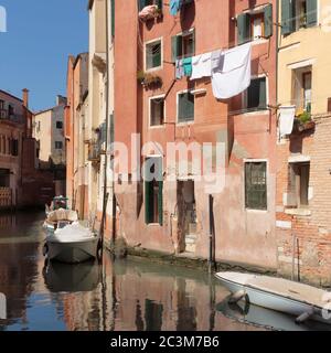 Wäschestaucken aus Fenstern entlang des rio del Gheto Kanals, Venedig, Italien Stockfoto