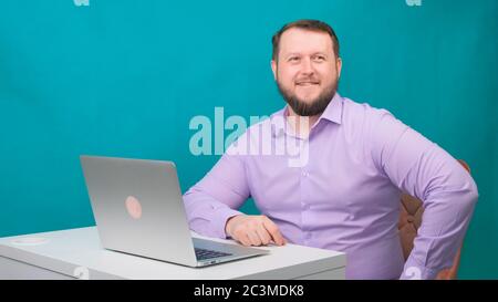 Junge glückliche Geschäftsmann lächelnd und sprechen in die Kamera. Porträt eines Mannes, der lachend auf seinem Laptop schaut. Mann arbeitet an seinem Schreibtisch in der Stockfoto