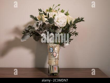 Selektive Schuss von Bouquet mit Blumen mit Seidenkreuz eingewickelt Hängen von ihm auf einem Tisch Stockfoto