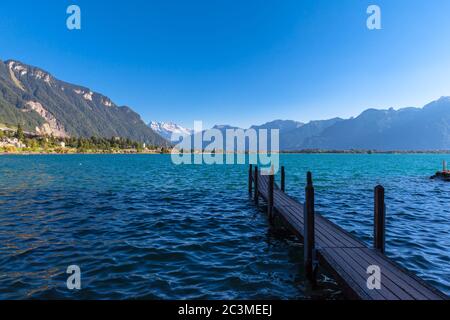 Atemberaubende Aussicht auf den Genfer See, mit den Gipfeln Dents du Midi der Schweizer Alpen im Hintergrund und einem kleinen Dock im Vordergrund, Montreux, Kanton Waadt, Schweiz Stockfoto