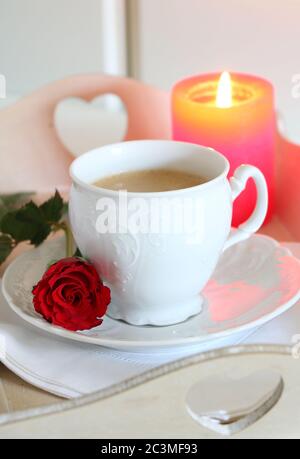 Tischdeko in weiß mit Kaffeetasse, Rose und Kerze Stockfoto