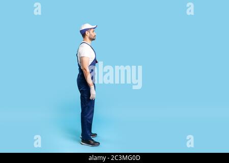 Volle Länge Profil von Handwerker in Uniform ruhig stehend, ernsthaft auf Kopierraum, warten auf Bestellung. Beruf der Dienstleistungsbranche, Hausreparatur Stockfoto