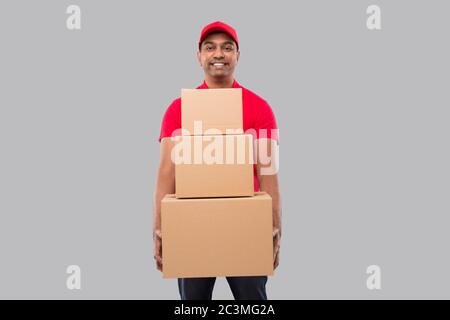 Lieferung Man Holding Karton Boxen Isoliert. Indian Delivery Boy lächelnd mit Boxen in den Händen Stockfoto