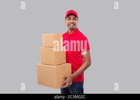 Lieferung Man Holding Karton Boxen Isoliert. Indian Delivery Boy lächelnd mit Boxen in den Händen Stockfoto