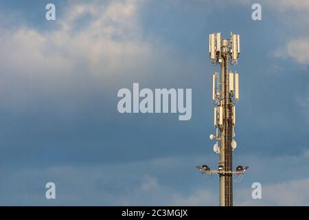 Elektromagnetische Strahlung. Telekommunikationsturm mit 5G- und 4G-Antennen zwischen den Wolken (mit Kopierplatz) Stockfoto