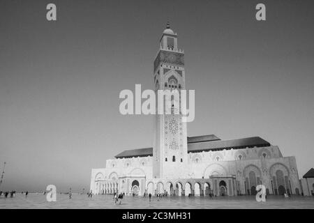 Eine Gruppe von Menschen, die während eines nebligen Nachmittags um die Moschee Hassan II. In Casablanca, Marokko, herum gehen und den Blick auf das Meer genießen Stockfoto