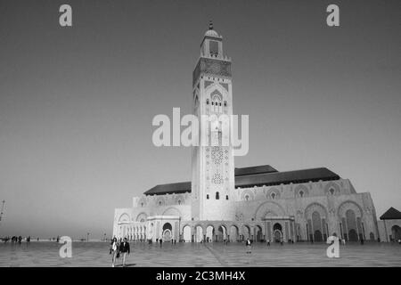 Eine Gruppe von Menschen, die während eines nebligen Nachmittags um die Moschee Hassan II. In Casablanca, Marokko, herum gehen und den Blick auf das Meer genießen Stockfoto