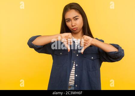 Schreckliches Ergebnis! Portrait von unzufriedenen Mädchen in Denim-Shirt zeigt Daumen nach unten, Missbilligung Zeichen, gestikulierende Abneigung zu schlechten Service, nicht einverstanden mit sugg Stockfoto