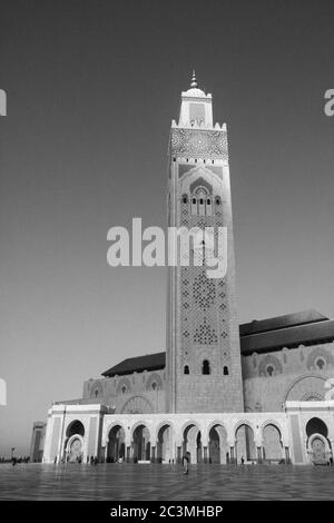 Eine Gruppe von Menschen, die während eines nebligen Nachmittags um die Moschee Hassan II. In Casablanca, Marokko, herum gehen und den Blick auf das Meer genießen Stockfoto