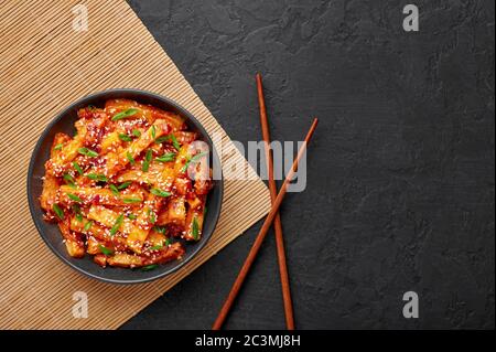 Honey Chili Potato oder Schezwan Aloo in schwarzer Schale auf dunkler Schieferplatte. Chilipartoffeln ist ein indo-chinesisches Gericht. Authentische asiatische Küche. Indisch Stockfoto