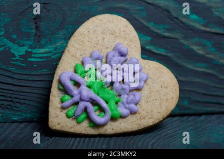 Lebkuchen mit Glasur verziert. In Form eines Herzens hergestellt. Auf gebürsteten Kiefernholzplatten. Stockfoto
