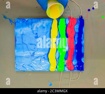 Hand gießt eine Linie von gelber Farbe über eine Künstler Leinwand Stockfoto