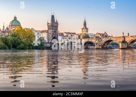 Karlsbrücke über die Moldau mit Schwanen bei Sonnenaufgang am frühen Morgen mit noch sichtbarem Mond am Himmel, Prag, Tschechien --- NIKON D750 Stockfoto