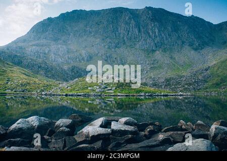 Atemberaubende Aufnahme eines kristallklaren Sees umgeben von Felsen Und hohen felsigen Berg Stockfoto