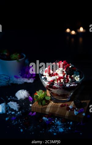 Selektiver Fokus von Vanilleeis mit mehreren Früchten in Ein süßes Glas auf einem Holzbrett Stockfoto