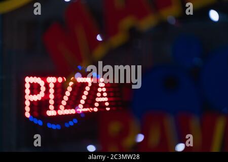 Farbenfrohe, hell beleuchtete Tafel einer Pizza-Ecke in der Nacht Stockfoto
