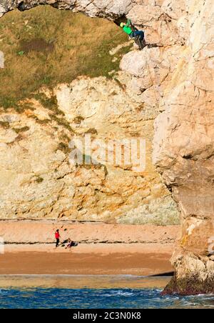 Ein einflüchiger Kletterer auf dem Felsbogen Durdle Door an der Jurassic Coast in Dorset, Großbritannien, von der Küste aus fotografiert Stockfoto