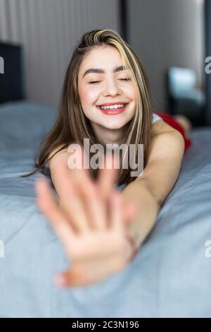 Junge Frau, die sich morgens in ihrem Bett ausdehnt Stockfoto