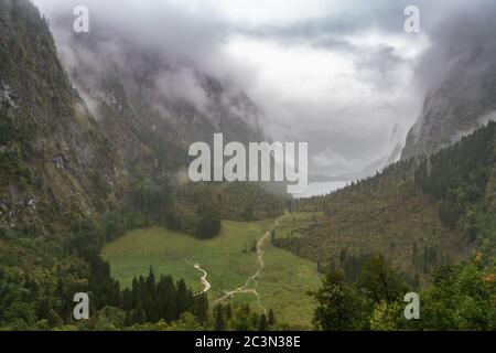 Idyllischer Blick auf den Obersee bei Königssee an einem nebligen Herbsttag auf dem Wanderweg hinunter zum See, Schönau am Konigssee, Bayern, Deutschland Stockfoto